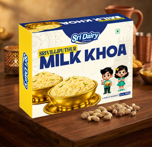 A box of Sri Dairy Srivilliputhur Milk KHOA on a wooden table, surrounded by cashews and pistachios, with warm background lighting and traditional cups.